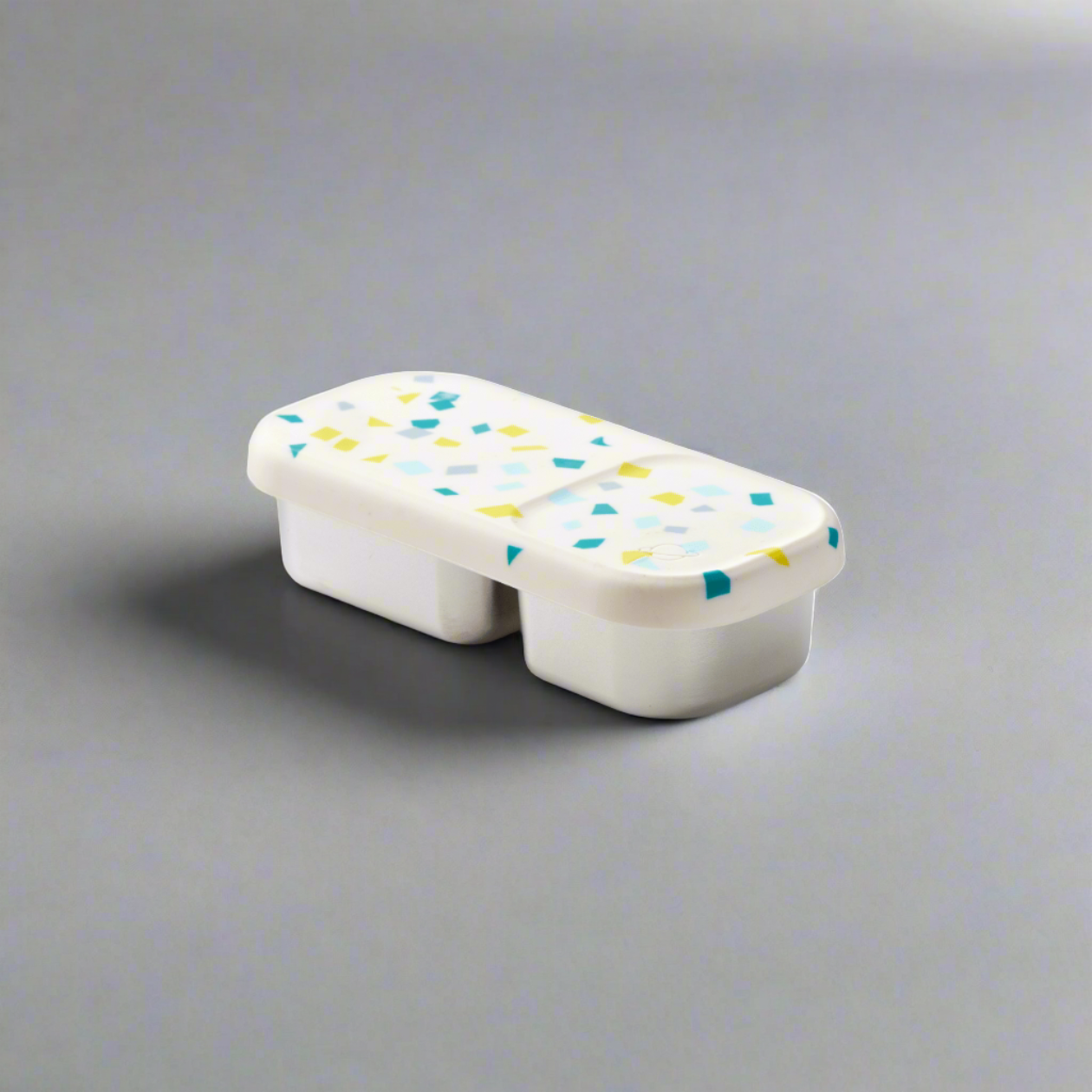 color::White Sand Terrazzo | Closed view of White Sand colorway of Day Tripper featuring white silicone lid with turqoise, blue and yellow flecks on a white background.