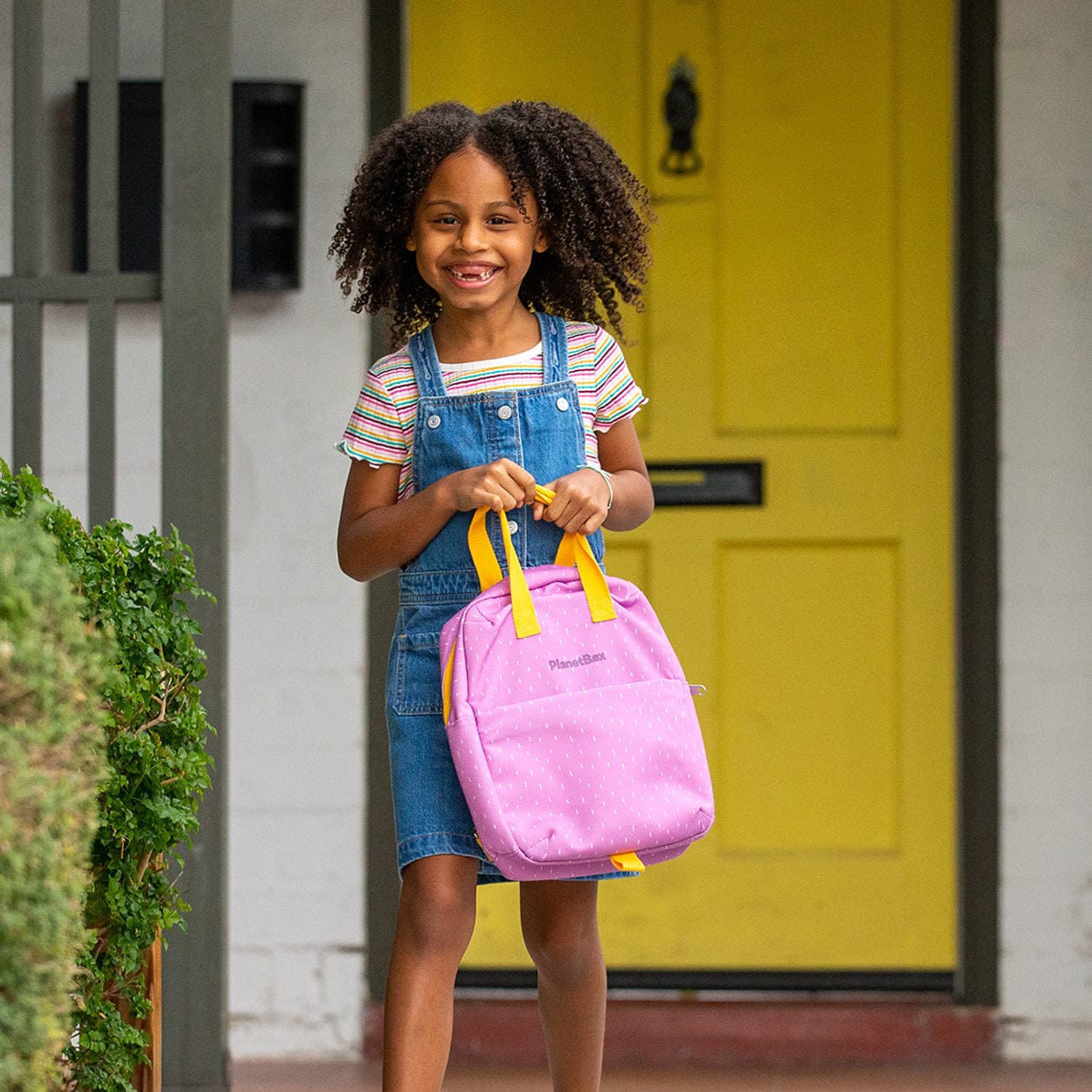 color::Pansy Dashes | Girl carrying Pansy Dashes lunch tote in front of house.